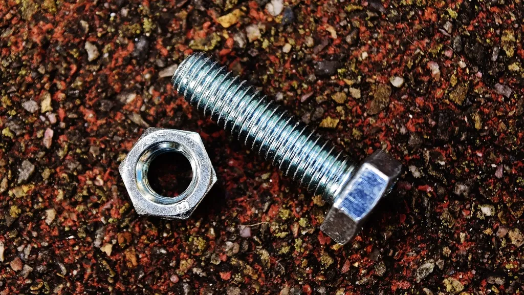 A steel bolt and hex nut on a textured surface