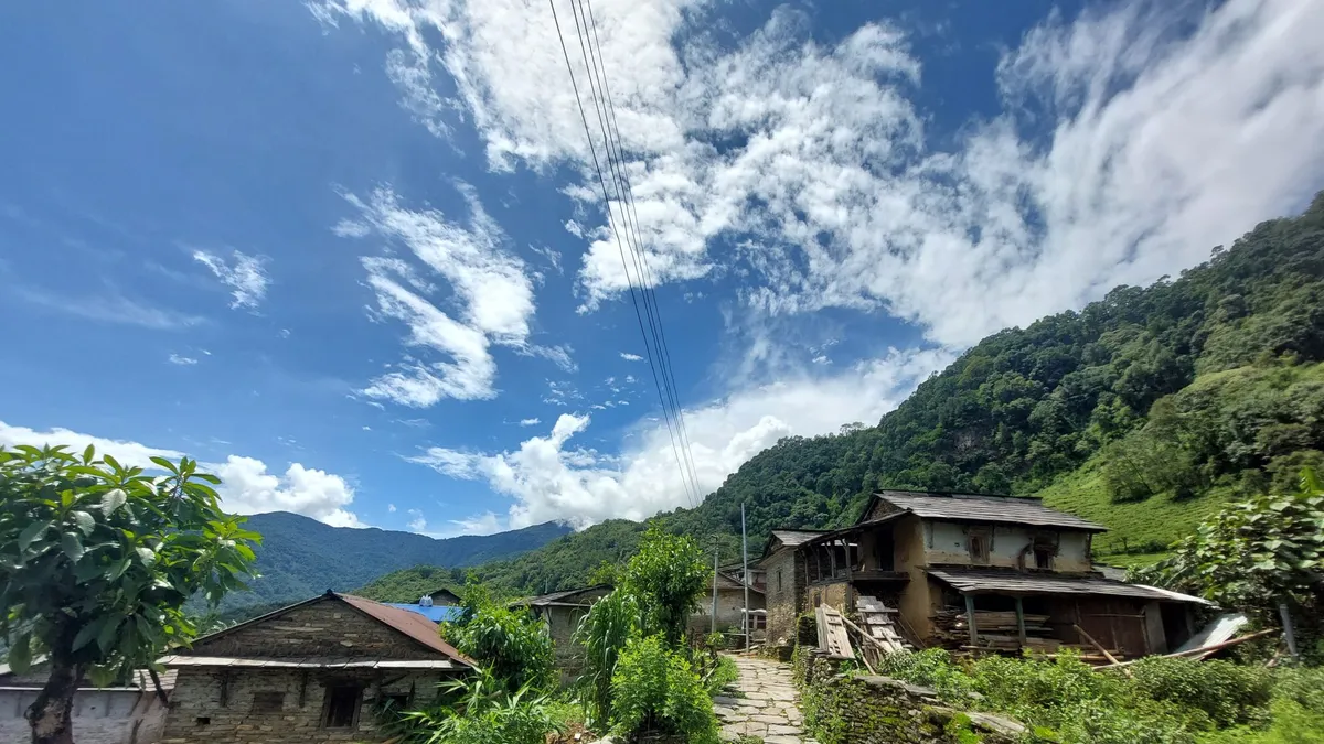 Traditional stone and wood houses in a green hillside village in western Nepal