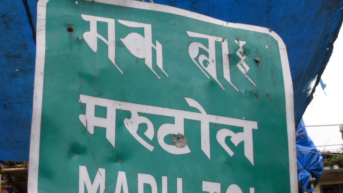 Green street sign in Kathmandu showing the place name Maru Tol in Devanagari and Roman script