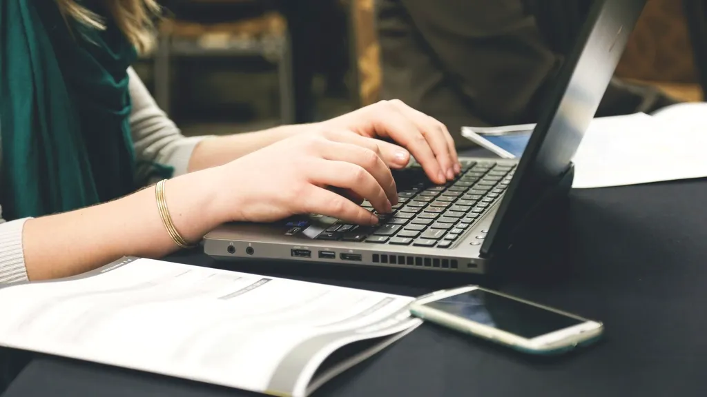 Professional typing on a laptop while updating an online profile