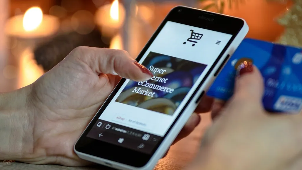 Person browsing an online shop on a smartphone while holding a payment card