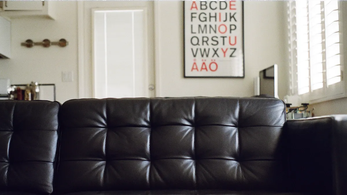 Black leather sofa in a bright living room with a framed alphabet poster