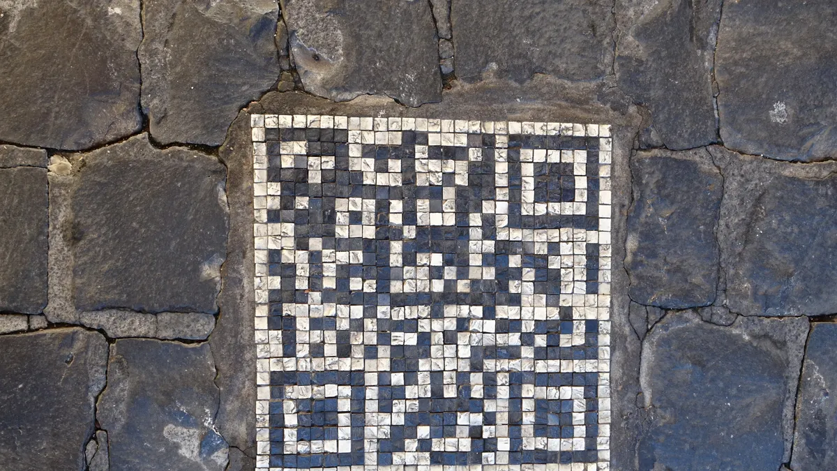 QR code made of black and white mosaic tiles set into a stone pavement
