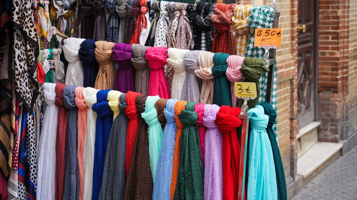 Colourful scarves hanging on a rack outside a shop with price tags
