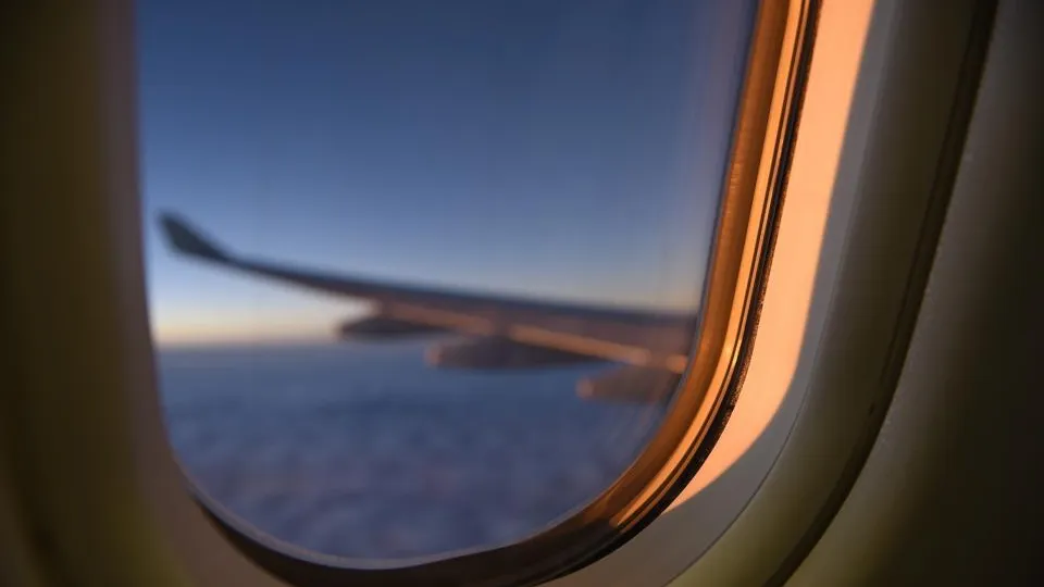 View of an aircraft wing through an airplane window at sunset